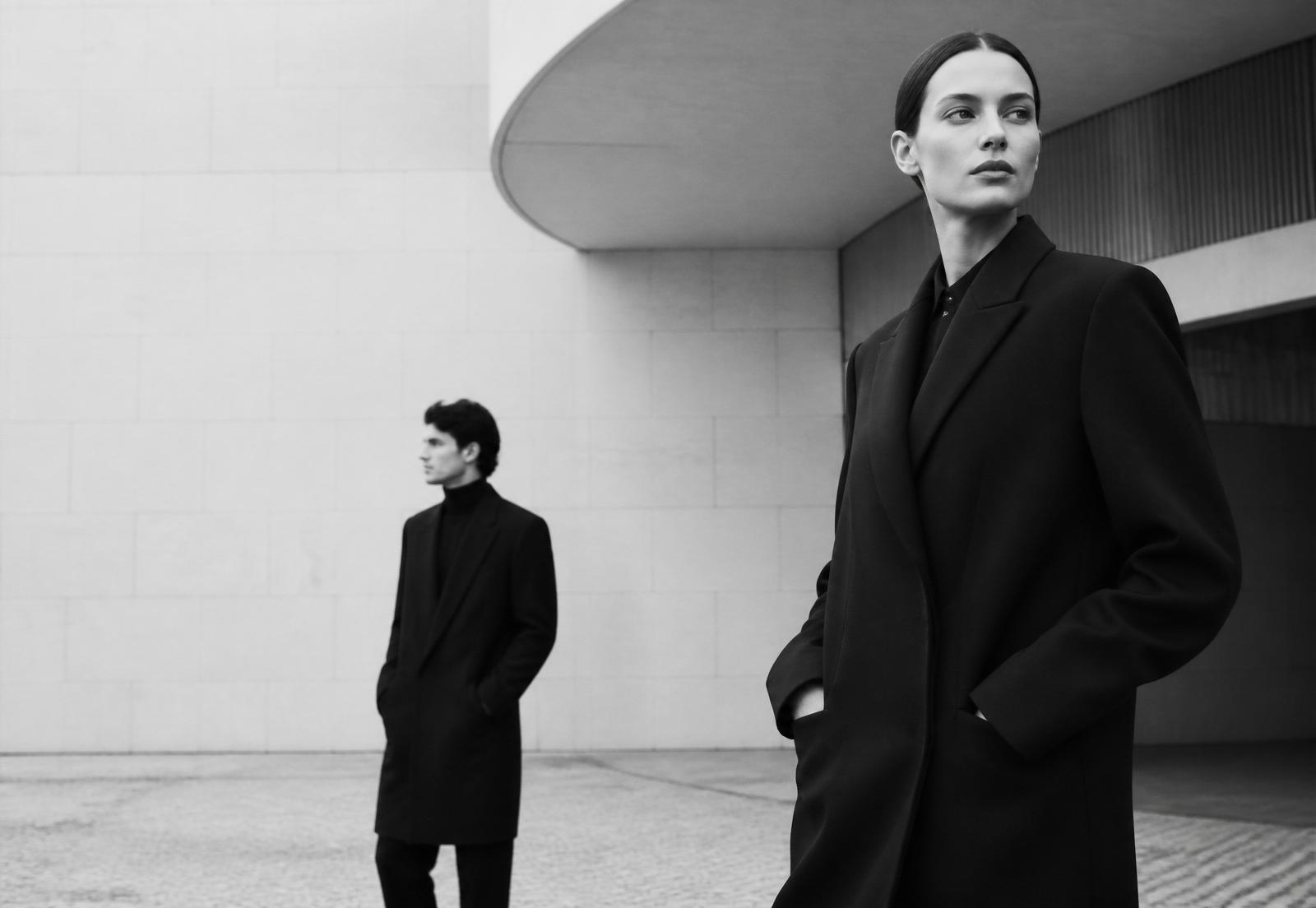 Modelos con abrigos negros de estilo minimalista frente a arquitectura moderna